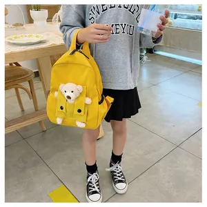Enfant tenant un sac à dos jaune avec un adorable ours en peluche 3D sur la poche