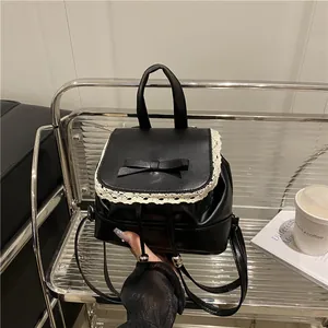Close-up of a women's black faux leather backpack with lace trim and bow detail