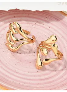 Detailed close-up of gold-plated plant-inspired adjustable rings on a pink plate