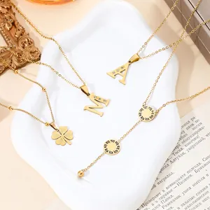 Variety of 18k gold titanium steel necklaces with letter and clover pendants on white plate
