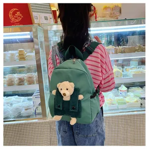 Vue de dos d'un enfant portant un sac à dos vert avec un ours en peluche mignon