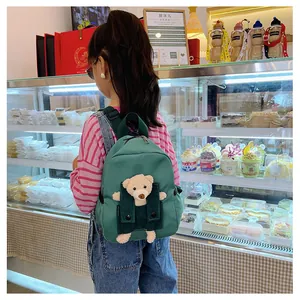 Vue arrière d'un enfant portant un sac à dos de maternelle vert avec un petit ours en 3D