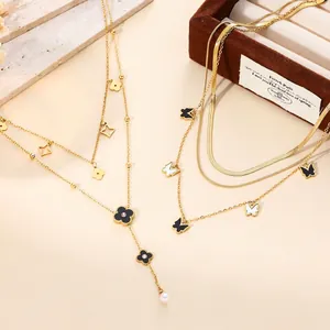 Close-up of 18k gold plated butterfly and clover charms on layered titanium steel chains