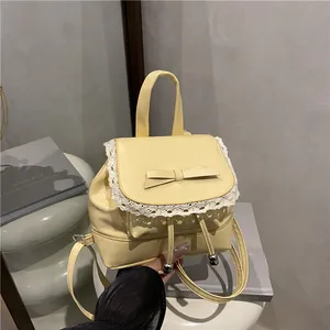 Detail view of yellow faux leather mini backpack with lace trim and bow accent