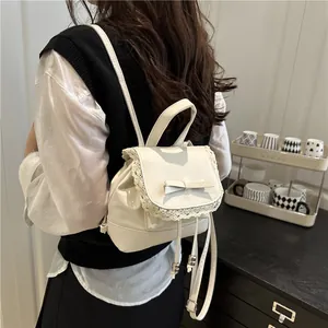 Close-up of a white faux leather mini backpack with lace trim and bow detail on model.