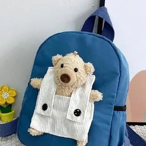 Gros plan d'un sac à dos bleu pour enfant avec ours en peluche et poche en velours.