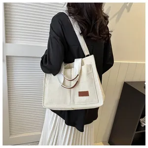 Large capacity cream corduroy tote bag worn as a shoulder bag in minimalist setting