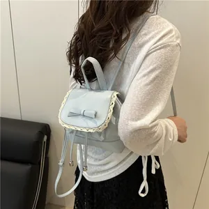 Detail view of a woman wearing a stylish light blue small backpack with bow and lace trim