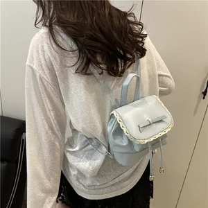 Back view of a light blue mini backpack with lace trim and bow worn by a model