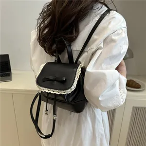 Detail of small black oil leather backpack with lace trim and bow on model's back