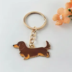 Close-up detail of a brown dachshund dog enamel keychain with a golden metal ring and chain