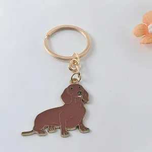 Detailed view of a golden metal dachshund dog keychain with brown enamel finish