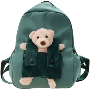 Joli sac à dos de maternelle vert foncé avec un ours en peluche dans une poche en velours.