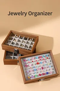 Close-up of walnut wood grain jewelry box with transparent lid and velvet ring slots.