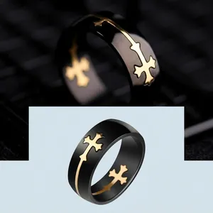 Detail view of a black titanium steel ring with a decorative gold cross inlay.