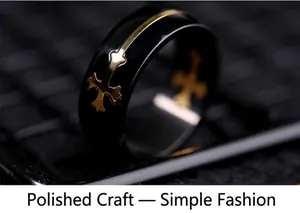 Close-up of a black titanium steel ring featuring a gold cross inlay and polished finish