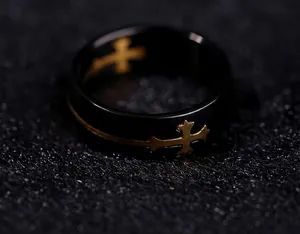 Close-up detail of the gold cross inlay on a polished black titanium steel men's ring.