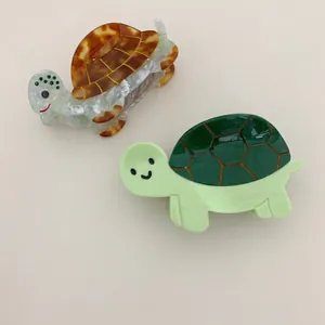 Pair of cute acetate turtle-shaped hair claw clips in tortoiseshell and green patterns.