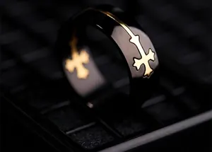 Close-up of a black titanium steel ring with an inlaid golden cross design