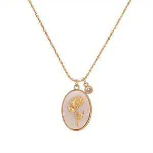 Close-up of gold-plated oval pendant featuring an intricate sunflower and small gemstone.