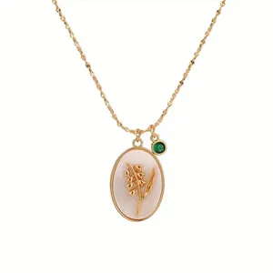 Detail of vintage oval pendant necklace with gold lily of the valley and green gem