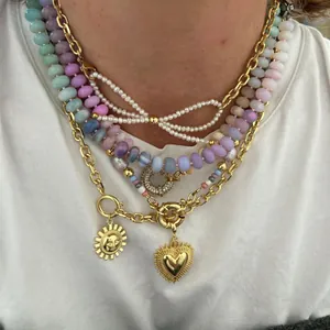 Vue détaillée de colliers de perles colorées avec pendentifs cœur et soleil dorés.