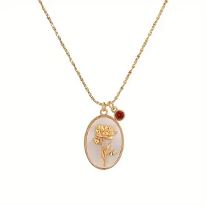 Close-up of vintage oval necklace with golden flower relief and red gemstone charm