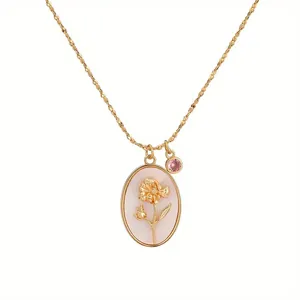 Detail view of vintage gold necklace with flower embossed oval pendant and pink stone.