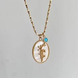 Close-up of vintage oval necklace with gold flower branch and blue gemstone charm