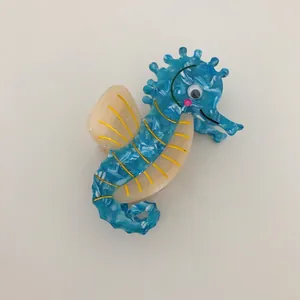 Macro view of a blue marbled acetate hair claw clip featuring a seahorse design.