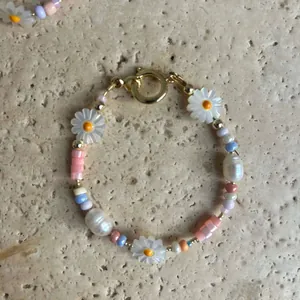 Détail du bracelet fait main avec marguerites, perles pastel et perles baroques.