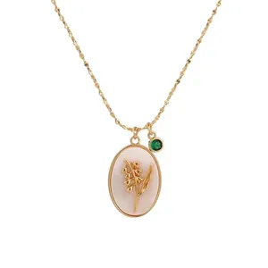 Elegant vintage gold oval necklace with lily of the valley pendant and green gemstone.