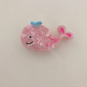Close-up detail of a cute pink whale-shaped acetate hair claw clip for women