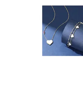 Detail view of gold-tone necklace and bracelet with heart-shaped white shell pendants