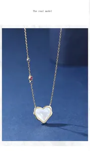 Close-up detail of gold heart necklace with white mother-of-pearl and colored stones