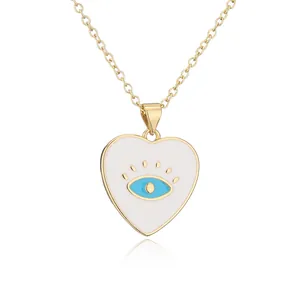 Close-up view of a gold plated heart necklace with a blue enamel evil eye pendant detail.