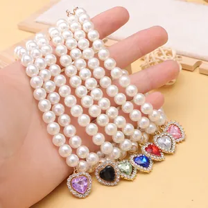 Close-up of pearl pet necklaces featuring various colorful heart-shaped crystal pendants