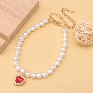 Close-up of white pet pearl necklace with a sparkling red heart-shaped pendant