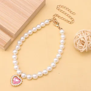 Close-up of cute pet pearl necklace featuring a sparkling pink heart-shaped crystal pendant