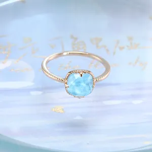 Primo piano di un anello vintage con gemma blu quadrata e fascia d'oro incisa
