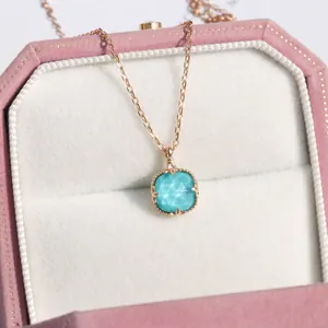Dettaglio di una collana con ciondolo in gemma blu quadrata in un portagioie in velluto rosa