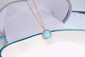 Primo piano di una collana retrò placcata in oro con ciondolo quadrato blu chiaro