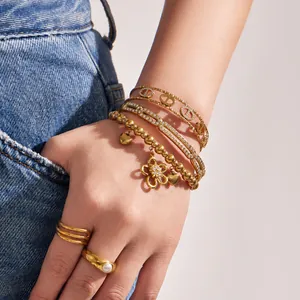 Stacked 18k gold-plated stainless steel bracelets with flower charms and CZ stones.