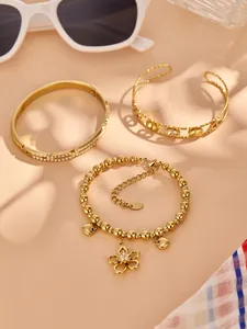 Detailed view of luxury gold jewelry set including flower charm bracelet and logo bangles