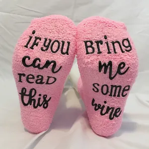 Cozy pink coral fleece socks with non-slip "Bring me some wine" lettering design.