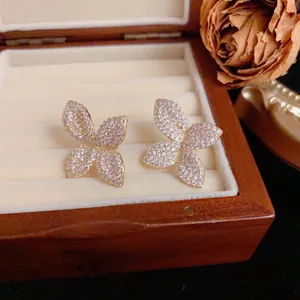 Close-up of sparkling full-diamond petal stud earrings in a wooden jewelry box
