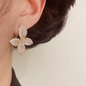 Elegant gold petal stud earrings with full micro-pave sparkling crystals shown on ear.