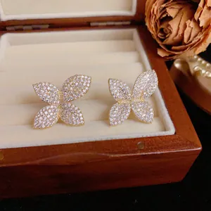 Sparkling full-zircon floral stud earrings in gold-tone displayed in a jewelry box