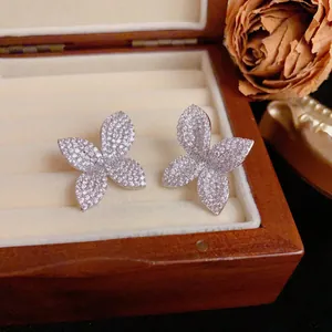 Detailed close-up of pavé crystal four-petal flower stud earrings in a wooden jewelry box