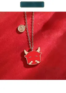 Detailed view of a red enamel Chinese zodiac ox pendant necklace with gold chain